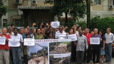 郑联语（左4起）及美纳西等人举起大字报及横幅，要求槟州政府解决水灾及土崩等问题。