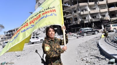 “叙利亚民主军”指挥官菲拉特周二在拉卡的地标Al-Naim广场挥舞旗帜，庆祝从IS手中夺回拉卡，结束IS对该市3年的统治。