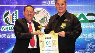 蔡振行（左）颁赠锦旗予郑金财，感谢他主持“一带一路，马来西亚－中国农业经贸论坛”开幕。（摄影：杨金森）
