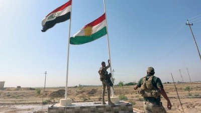伊拉克士兵进入基尔库克，升起伊拉克国旗，并降下库德族的旗帜（右）。