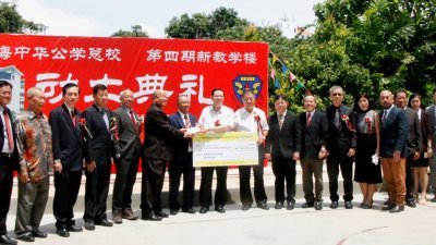 林冠英（左8）在中华总校董事长杨玉箴（左7）等见证下，将10万令吉支票移交给董事会财政陈世平（左6）。