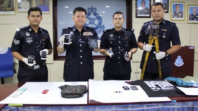 黄光顺（左2）与警官向媒体展示逮捕“万哆党”成员时，所起获的手提电话及犯案工具。