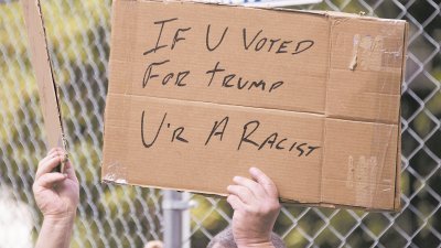 美国示威者周四在白宫外示威，高举标语“如果你投特朗普，你就是种族主义者”。