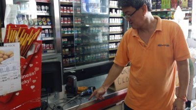 超市东主吴振德指，柜台收银机遭劫匪劈短电线，将整个收银机抱走。