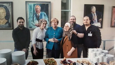 来自叙利亚的杰玛提（右3）为逃离内战跑到德国，她在柏林展开餐饮事业，她做的中东菜连总理默克尔（右4）也为之倾倒。
