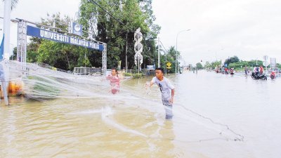 玻州发生水灾期间，两名灾民在玻璃市大学外淹水的马路中央撒网捉鱼。