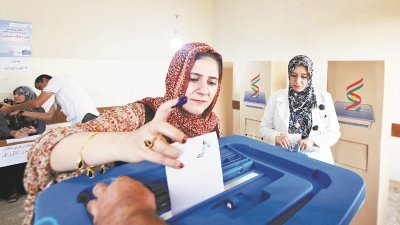 在伊拉克库尔德自治区首府埃尔比勒的一所投票站，一名库族妇女投票选择是否要独立公投。