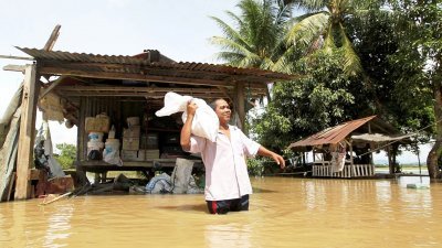 笨同县部分地区积水未退，其中一名灾民忙著把货仓里的稻米移往其他安全区。