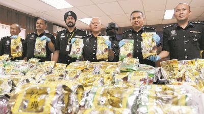 莫末沙烈（中）在建功警察陪同下，展示大批被包装成中国茶的冰毒。