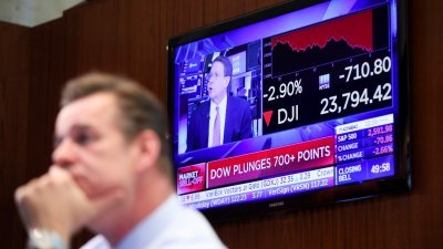 美国纽约证券交易所的交易员，神色凝重看著股票走势，墙上的电视播著当天股市行情的新闻。纽约股市三大股指周五收盘下跌。