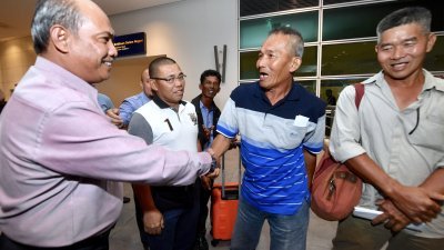 梁绵盛（右2）回到吉隆坡第二国际机场时，接受嘉玛鲁丁奥曼（左）的祝贺。