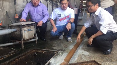 黄伟益（左起）、刘敬亿及王宇航巡视七条路巴刹小贩中心的排污系统。