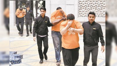 3名身穿橙色扣留服的嫌犯在反贪会官员的押送下，抵达布城推事庭。