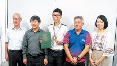 庄品祥（左3）在中华中学董事会总务林琮淞（左起）、杨来福、家协主席高泉标及刘世瑛陪同下，展示在国际奥林匹克物理比赛中获得的铜牌。