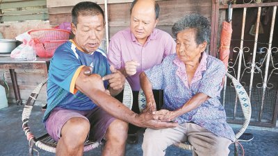 朱友发（左）向上门探访选民的九洞州议员谢保恒（中）展示右手臂的肉瘤，在旁的萧桂英也爱莫能助。