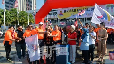 火炬手把火炬传递给吉隆坡选手代表，并带领骑车选手，绕行市中心。在场见证的还有章瑛（右4）和大马奥委会主席拿督斯里诺扎（右6）。 （摄影：曾钲勤）