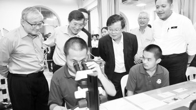 曹观友（后排左3）在袁俊良（左起）、黄炳意、陈景祥及行政议员阿菲夫的陪同下， 观看一名中学生如何利用显微镜进行罪证分析。 （摄影：-蔡开国-）