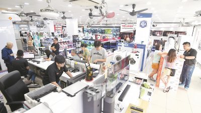 适逢公共假期，电器店挤满许多顾客，把握零税率的“蜜月期”购买新电器，以致员工也十分忙碌。（摄影：伍信隆）