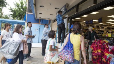 飓风来袭，夏威夷超市店员周四在店铺窗户钉上木板，避免落地窗遭到破坏，民众则赶往超市购买日用品，为飓风可能带来的灾情做准备。