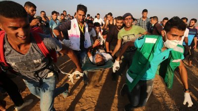 加沙地带以巴边境周五有爆发示威冲突，巴勒斯坦救援人员将一名伤者抬离现场。