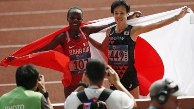 巴林的女子马拉松冠军切里莫（左）和日本亚军野上惠子，拿著国旗让摄影拍下历史性一刻。 