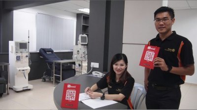 麦提勒斯（右）与秘书刘玉珍展示峇株巴辖扶轮社的电子支付二维码。