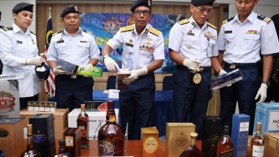 莫哈末朱比利（中）向媒体展示大马海事执法机构起获的走私香烟及酒精饮料。