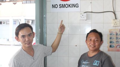 黄湫权（左）指若要张贴13张禁烟告示牌，将不懂要怎么 贴。旁为黄志忠。