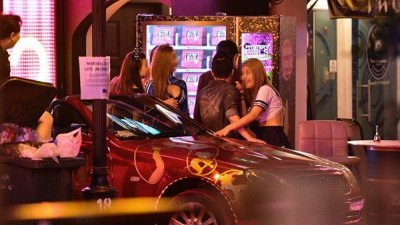 “神秘酒吧”外放著名车、贩卖机，性感女郎看到顾客就会 趋前迎客。（海峡时报）
