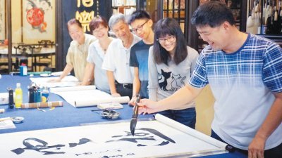柔州书艺协会会长杨金荣（右）每年配合不同生肖所题写的春联。图为他教导学生写书法。