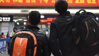 背著行李的年轻人，在广州火车站候车厅里，查看大屏幕显示的乘车信息。今年春运共计40天，于2月1日启幕至3月12日结束。