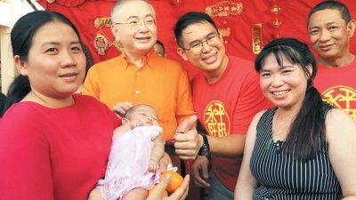 魏家祥（左2起）与林添顺派发柑及红包给予一名抱著婴儿的选民。