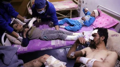 叙利亚无视联合国停火决议，继续炮轰，甚至化武袭击反抗军据点东古塔，10岁男童奥马尔（中）在空袭中失去其他家人，他和7岁的妹妹和父亲则身受重伤。-法新社-