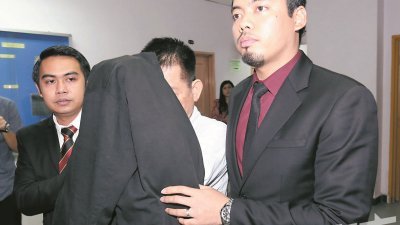 被告（左2）用黑色大衣遮脸，躲避媒体镜头。（摄影：刘维杰）