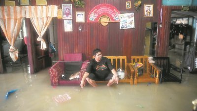 关丹依然是受灾最严重的地区，图为一名古当拉骚村民阿都拉辛（39岁）无奈坐在木椅上等待洪水退去。