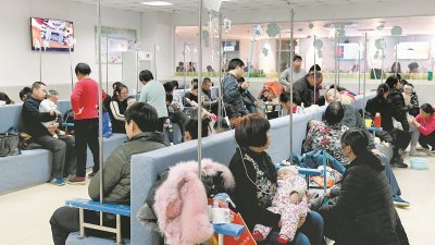 郑州市儿童医院输液大厅内挤满流感病患，许多病童在家长的陪同下输液。