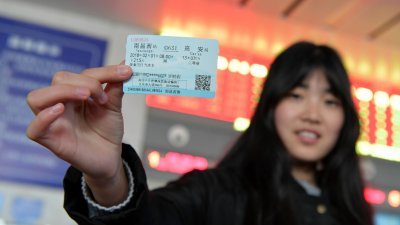 中国全国各地自3日开始在网络、电话平台开售春运首日火车票。图为当天在南昌铁路局南昌西站售票处，一名旅客展示她刚刚取到的春运首日火车票。
