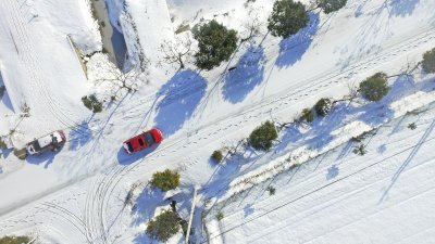 中国多地持续多天下起大雪。在江苏省淮安市洪泽区，汽车在白雪覆盖的路面上行驶。