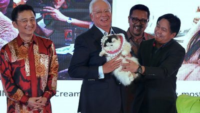 大马爱猫者协会主席汤姆斯在马来人总商会宴会上，赠送一只名为“甜心”（Sugar）的名种猫予纳吉（左2）。左为丹斯里戴良业及马来人总商会主席里查弗里斯（右2）。