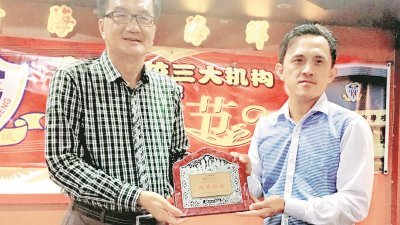 文明学校董事长黄春成（左）赠送纪念品予吴俊益。