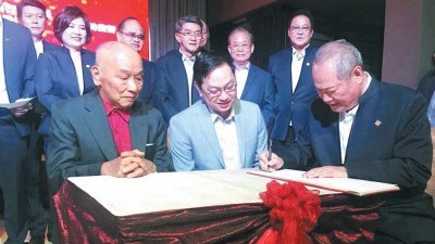 林峇（左起）与潘伟斯在新山中华总商会第46届（2018-2020年度）董事会暨属下青商团理事会就职典礼上，见证新任会长刘国胜签下宣誓就职书。