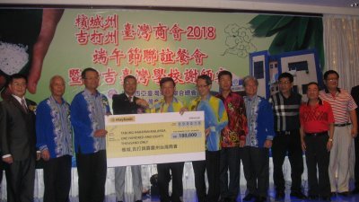 李鸿隆（左3起）和林永昌移交18万令吉的模拟支票给曹观友，并由刘子健等人陪同。