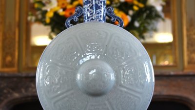 在法国蒙巴宗拍卖的抱月瓶青瓷器，瓶身侧面是白色蓝底藤枝穿花纹图案，瓶底刻有乾隆的六字篆体方形印章。