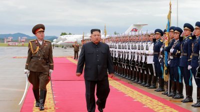 朝鲜最高领导人金正恩（中）周日启程飞往新加坡前，在平壤机场视察荣誉卫队。