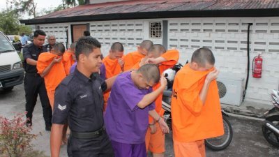 身穿橘色及紫色警局拘留所嫌犯衣服的被告，在看到媒体趋前拍照时，纷纷以用手及上衣遮脸躲避镜头。