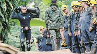 泰国少年足球队的12名球员和教练，受困在清莱府的洞穴内十多天，救援队伍正想方设法把他们救出。这是一名潜水人员，抬著氧气筒离开洞穴。
