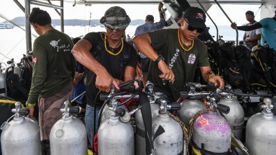 泰国潜水员周六在普吉岛一处码头检查氧气罐，准备潜入海中搜寻受困船内的失踪者。