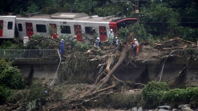 日本佐贺县唐津市周六因连日暴雨造成土崩，一辆行驶中的列车因此脱轨，救灾人员在现场救援及清理倒下的树木。