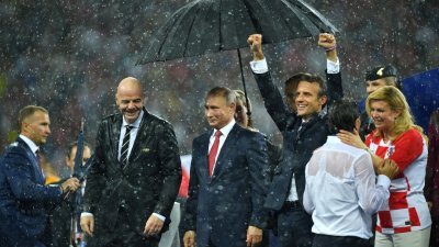 俄罗斯世界杯决赛的颁奖典礼下起大雨，只有俄罗斯总统普京（中）及时获得工作人员撑伞，克罗地亚总统基塔罗维奇（右起）、法国总统马克龙和国际足联主席因凡蒂诺（左2），唯有淋雨。