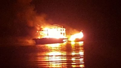 货船火势猛烈，将漆黑的河口照得明亮，令人触目惊心。